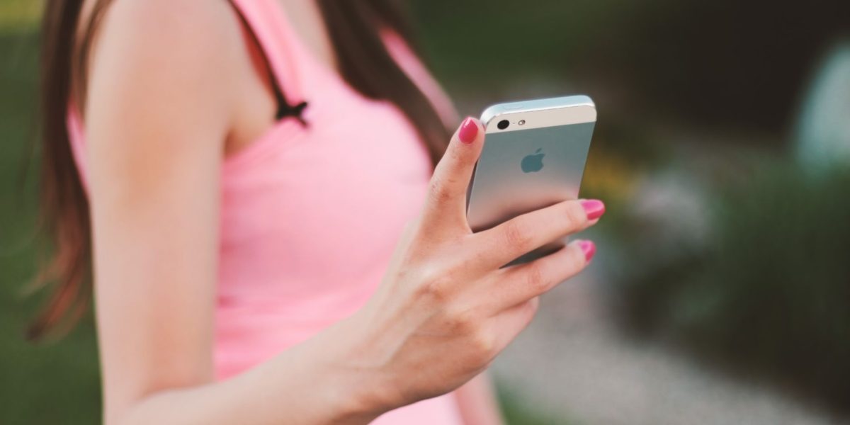 Mulher usa um smartphone ao ar livre em um dia ensolarado.