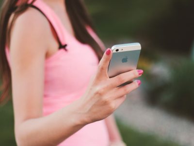Mulher usa um smartphone ao ar livre em um dia ensolarado.
