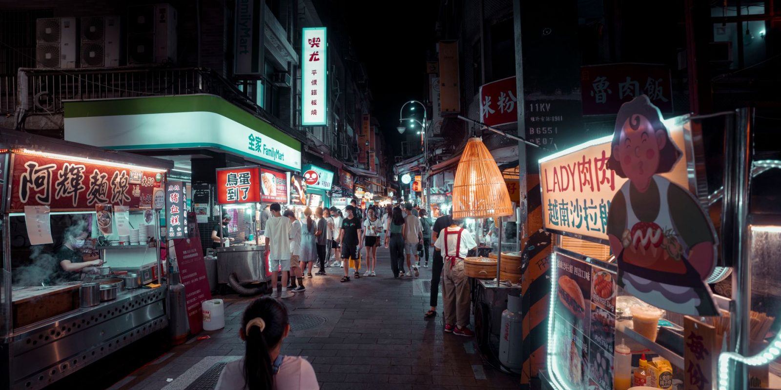 Feira Noturna de Jundiapeba começa a funcionar aos sábados em Mogi das Cruzes 17 Feira noturna ao ar livre, com barracas de comida iluminadas e pessoas circulando entre os estandes.
