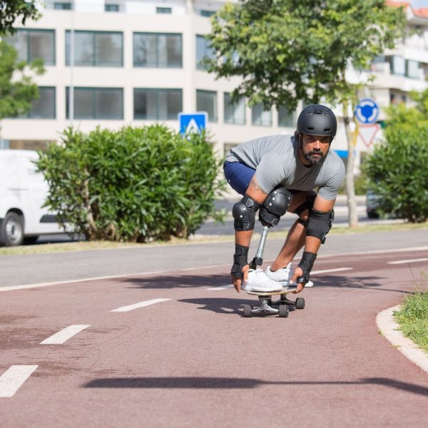Pessoa com prótese na perna andando de skate ao ar livre em um dia ensolarado