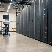 Armários metálicos com servidores, dispositivos de rede e cabos no interior de um data center moderno.