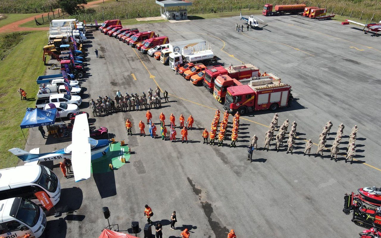 Vista aérea de caminhões, veículos de emergência e equipes reunidos durante um exercício de treinamento.