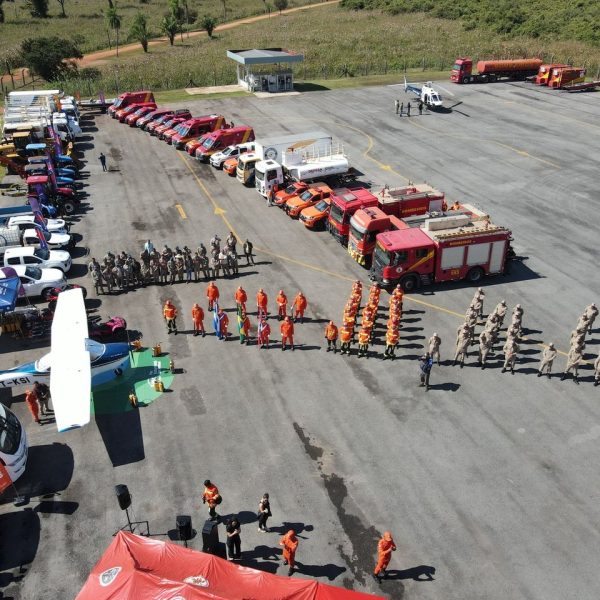 Vista aérea de caminhões, veículos de emergência e equipes reunidos durante um exercício de treinamento.