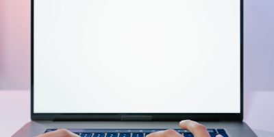 Mãos digitando em um laptop com a tela em branco