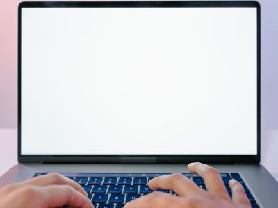 Mãos digitando em um laptop com a tela em branco